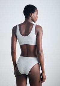 Set di reggiseno in cotone grigio e slip a vita alta. Il reggiseno presenta una schiena a forma di U, mentre gli slip hanno un design elegante e minimalista. Texture liscia.
