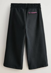 Čierne tepláky s elastickým pásom a zadnou vreckom. Obsahujú ružový nápis "ALL SAINTS" a hladkú textúru. Široký strih.