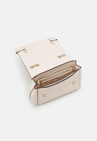 Beige handväska med en texturerad yta, guldfärgad hårdvara och två tryckknappar. Inuti finns en ficka med dragkedja och ett huvudfack.
