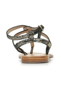 Sandali neri in pelle con un design a strisce decorato, suola piatta in legno e una fibbia regolabile per fissare il piede.