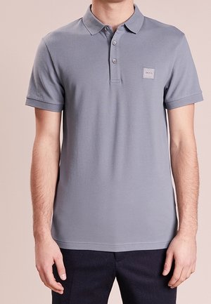 Szara koszulka polo wykonana z miękkiej bawełny, z trzema guzikami i małą naszywką z logo na lewej piersi, z krótkimi rękawami.