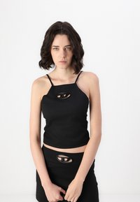 Black sleeveless cropped top with thin straps and oval cutout detail at the chest. Smooth texture and fitted design. Skirt matches with cutout.