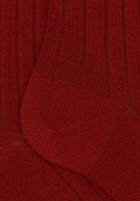 Calze rosse lavorate a maglia con una texture a coste e una costruzione senza cuciture. Il tessuto sembra morbido e resistente, ideale per un uso casual.