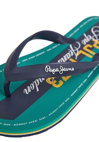 Tamsiai mėlyni šlepetės, pagamintos iš gumo, su tekstūruota padanga, kurią puošia žalia ir juoda grafika, ir baltas "Pepe Jeans" logotipas ant dirželio.