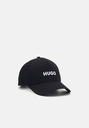 Casquette de baseball noire avec visière courbée et logo "HUGO" blanc brodé à l'avant, présentée sur fond blanc.