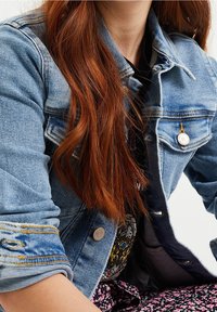 Jeansjacka i ljusblått, med knäppning framtill, vikta ärmar och synlig sömnad. Texturerat tyg med en avslappnad passform.