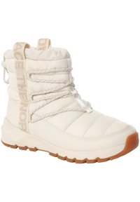 Bota aislante blanca con diseño acolchado, suela texturizada de goma, cordones ajustables y una lengüeta para tirar.