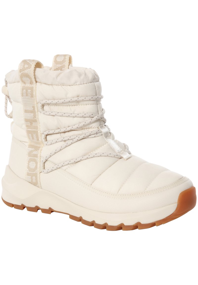 Bota aislante blanca con diseño acolchado, suela texturizada de goma, cordones ajustables y una lengüeta para tirar.