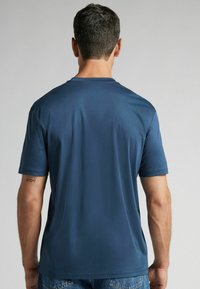 T-shirt à manches courtes bleu marine avec un col ras du cou, texture lisse et ourlets cousus. Présente une coupe décontractée et un design casual.