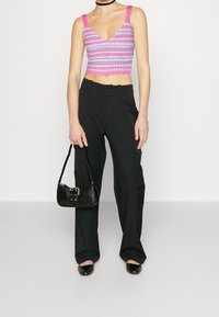 Kort topp med rosa och grå ränder, breda axelband, i kombination med svarta cargo-byxor och en liten svart handväska. Platta svarta skor.