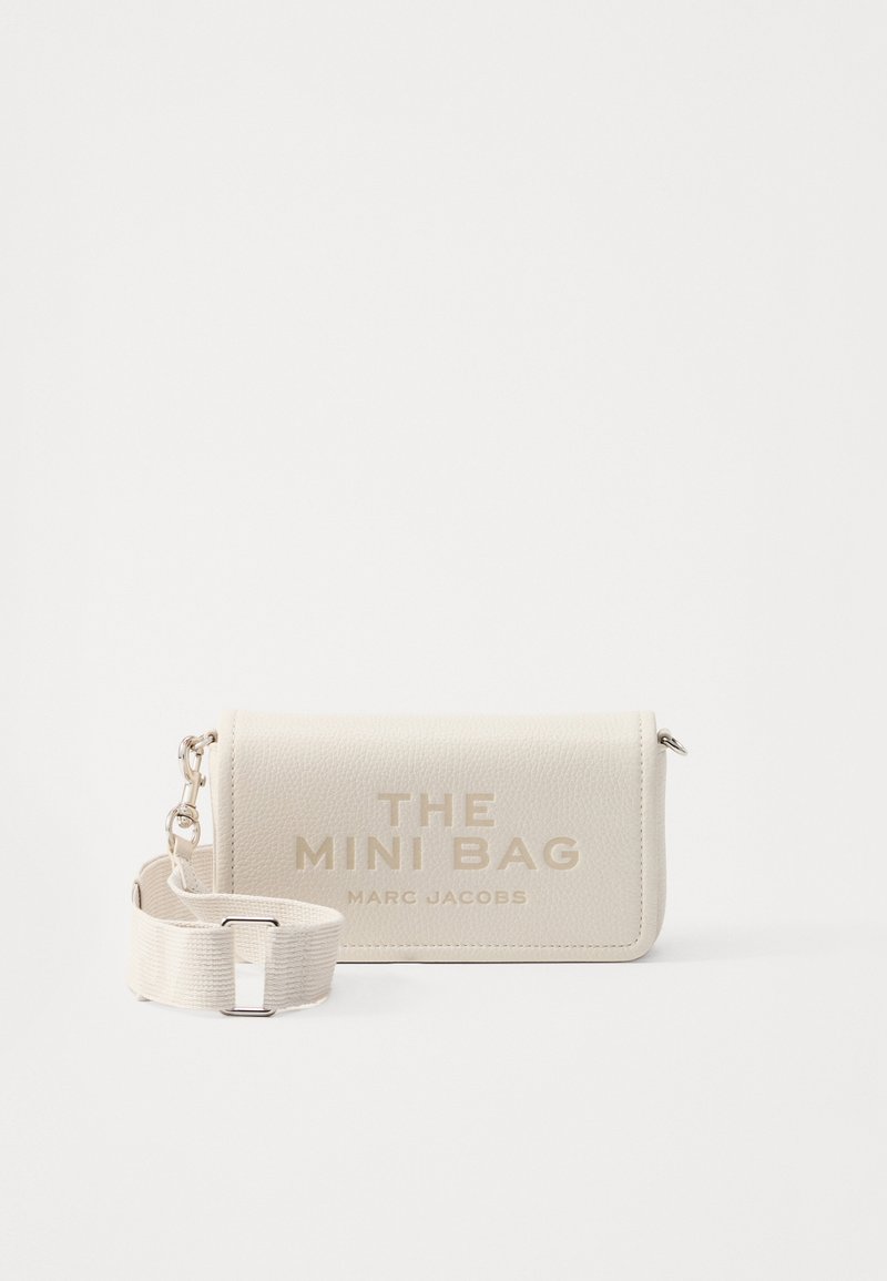 Beige läder mini-väska med en texturerad yta. Har en avtagbar rem och präglad text: "THE MINI BAG" och "MARC JACOBS."