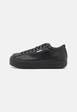 Sneaker in pelle nera con punta rotonda, finitura testurizzata e suola piatta in gomma. Presenta lacci neri e un piccolo etichetta del marchio sul lato.