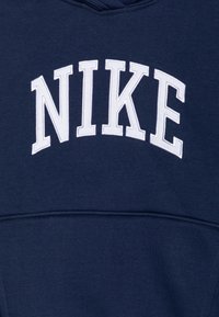 Navyblauwe sweatshirt met een capuchon, gekenmerkt door een groot, wit geborduurd "NIKE" logo op de borst. Zacht materiaal met een gladde textuur.