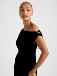 Μαύρο βελούδινο φόρεμα με ανοίγματα στους ώμους και ρεβρέ λεπτομέρεια στη μέση, στολισμένο με τρία χρυσά διακοσμητικά κουμπιά στον ώμο.