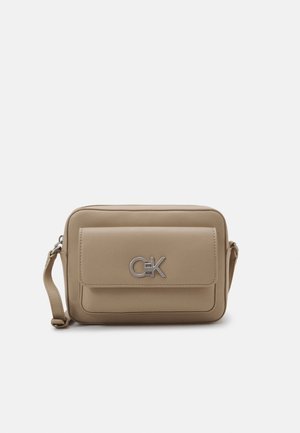 Sac bandoulière rectangulaire beige avec poche à rabat avant et détail logo métallique, sangle réglable et design minimaliste sur fond blanc.