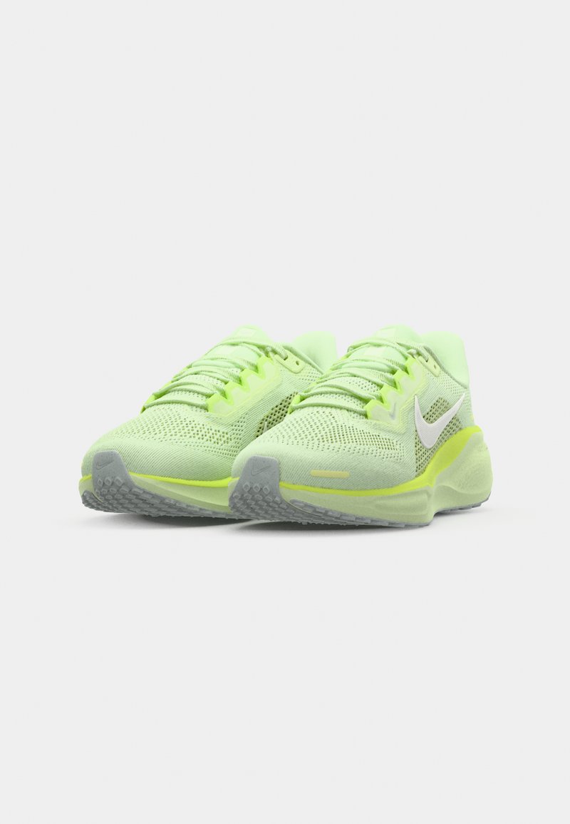 Zapatillas deportivas verde claro con parte superior de malla, detalles reflectantes, suela acolchada y suela de goma gris texturizada. Los cordones combinan con el color del zapato.