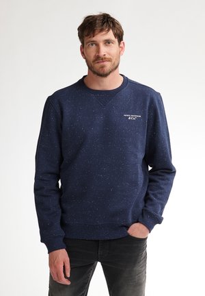 Marineblauwe sweatshirt van een textuurstof met witte spikkels. Heeft een ronde hals en een klein logo op de borst. Lange mouwen.