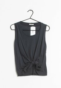 Haut sans manches bleu marine foncé en tissu doux, avec un détail de nœud torsadé à l'avant et une coupe décontractée. Suspendu à un crochet noir.