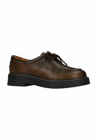 Chaussure en cuir marron avec une forme arrondie et une texture lisse. Elle possède une semelle noire épaisse et un laçage assorti.