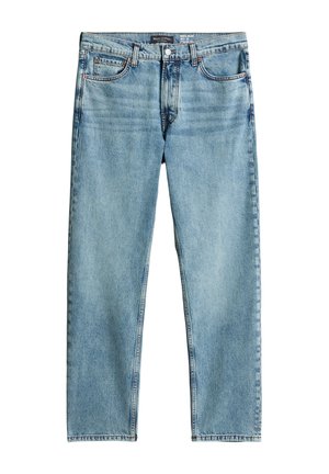 Junger Mann trägt ein schlichtes weißes T-Shirt, hellblaue Jeans und dunkelbraune Schuhe, steht vor einem weißen Hintergrund.