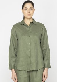 Oliwkowa, długi rękaw, koszula zapinana na guziki z teksturowanej tkaniny, z kołnierzykiem i jedną kieszonką na piersi. Prosty design, luźny krój.