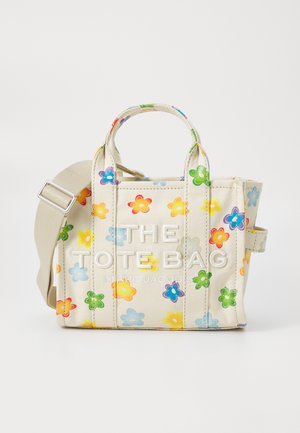 Bolso de lona en color crema con estampado floral multicolor, dos asas superiores y una correa ajustable y desmontable. Presenta letras en relieve.