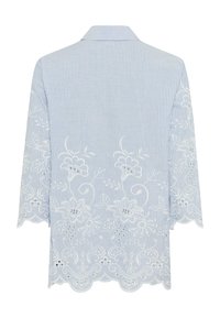 Blouse rayée bleu et blanc à manches longues, broderie en dentelle blanche florale sur le bas du dos, les manches et l'ourlet festonné.