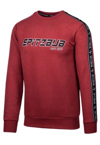 Red sweatshirt with long sleeves, ribbed cuffs, and round neckline. Features black text "SPITZBUB EST. 2017" on the front and side stripe details.