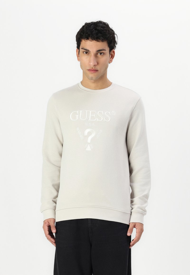Sudadera gris clara de material suave, con cuello redondo y mangas largas. Logo bordado y elementos de diseño en la parte delantera.