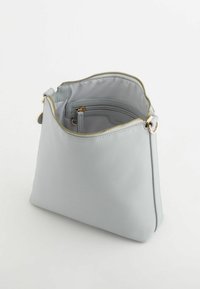 Vaaleanharmaa olkakassi, joka on valmistettu teksturoidusta materiaalista. Kassi sisältää vetoketjukiinnityksen ja kultaiseksi sävytettyä metalliosaa. Sisäpuolella on pieni tasku.