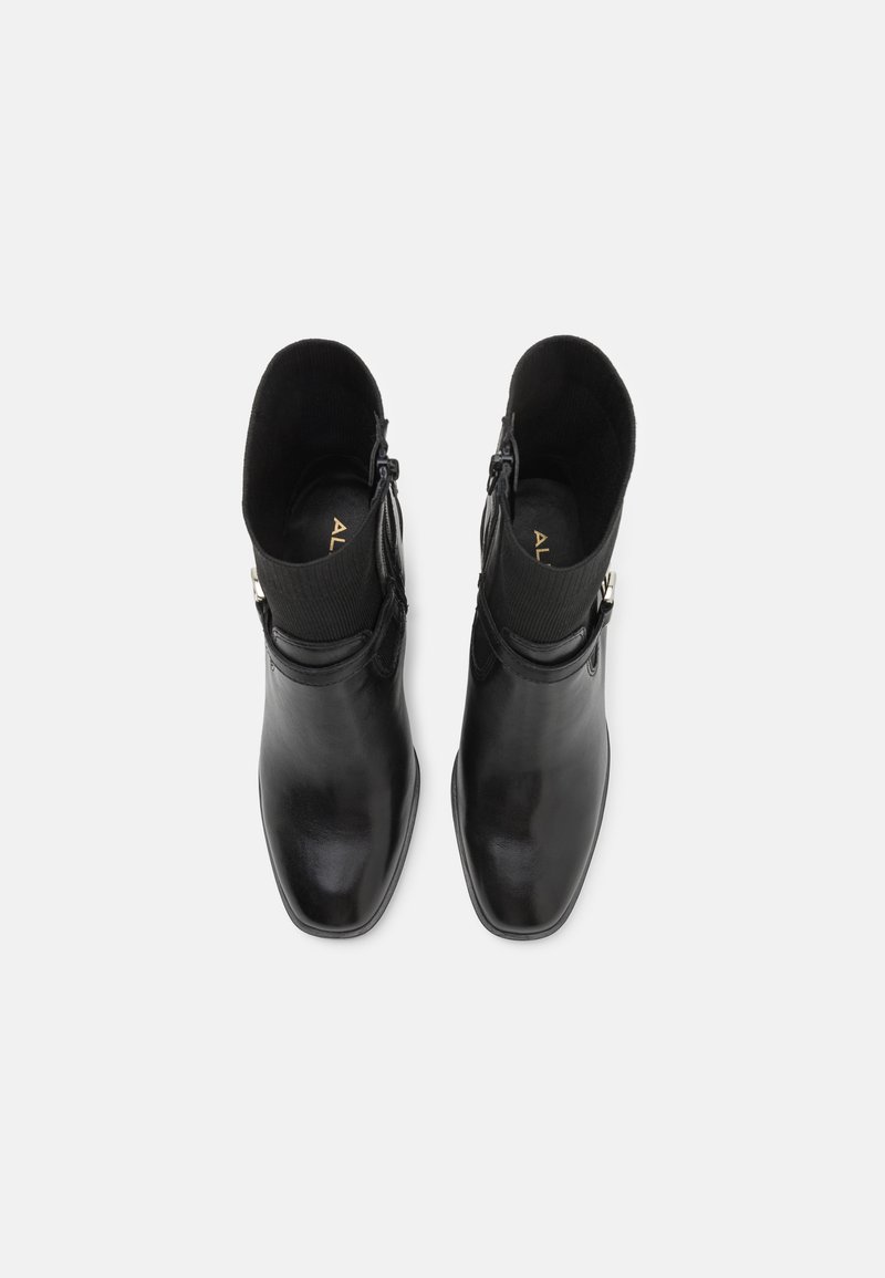 Stivali alla caviglia in pelle nera con finitura opaca, punta squadrata, colletto a coste simile a un calzino e chiusura con zip laterale. Design minimalista con dettagli accentuati.