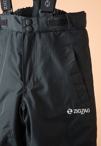Pantalon d'hiver noir avec bretelles ajustables, deux poches latérales, et un logo "ZIGZAG" brodé sur le devant. Confectionné en matériau durable.