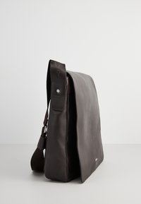 Borsa messenger in pelle marrone con forma piatta, cinturino regolabile e superficie testurizzata. Presenta un logo vicino al fondo.