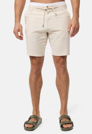 Beige shorts van textiel met een trekkoord in de taille. Draag ze met groene sandalen met een dubbele band en dikke zolen.