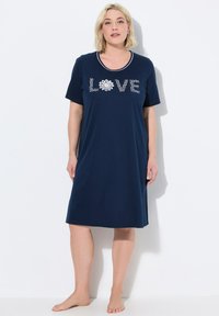 Tmavě modrá noční košile s krátkými rukávy a kulatým výstřihem, s nápisem "LOVE" bílými písmeny a květinovým akcentem. Měkká textura, podobná bavlně.