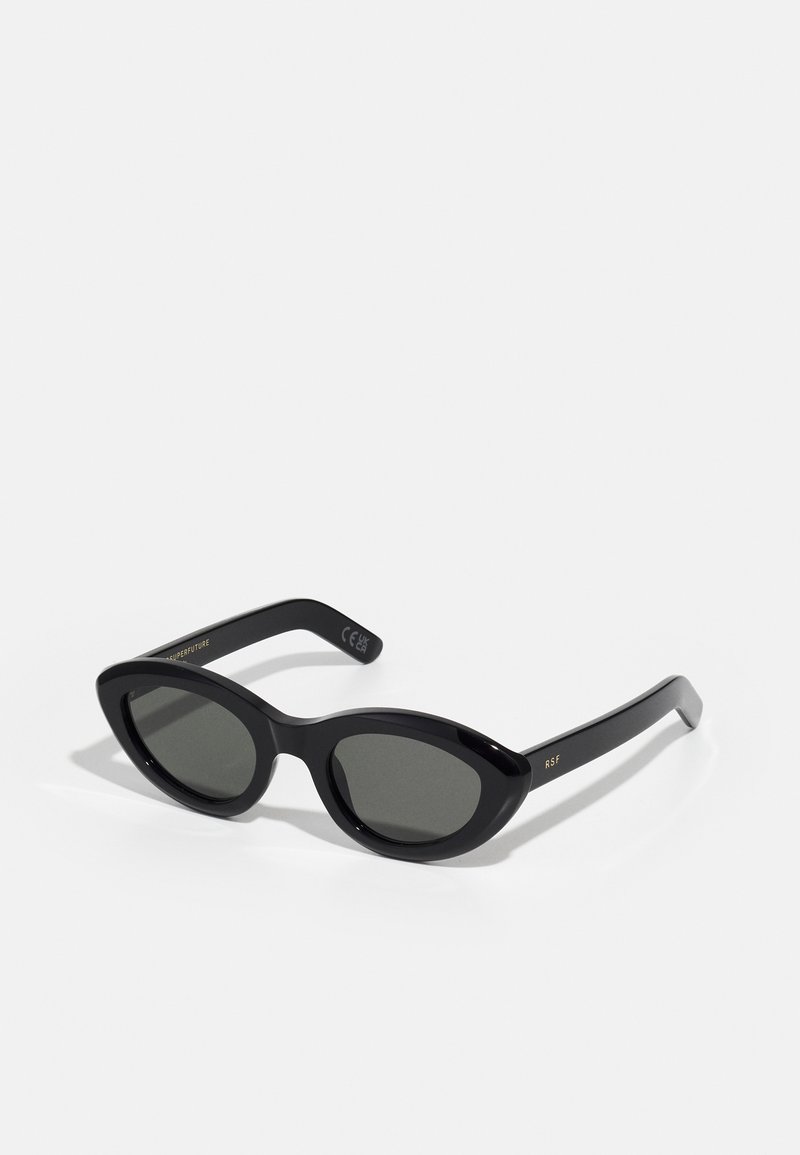 Gafas de sol negras con forma redondeada de ojo de gato y lentes oscuros. Fabricadas en plástico brillante, con sutil texto dorado en las varillas.
