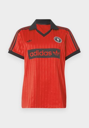 Camiseta de fútbol roja de Adidas con cuello negro, puños de manga negros, rayas negras en los hombros y logotipos de Adidas en el pecho y el lado izquierdo.