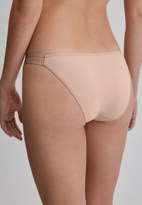 Lichtbeige damesondergoed met een gladde textuur, minimalistisch ontwerp en dunne, dubbele schouderaccenten.