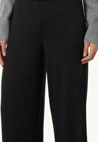 Pantalons larges noirs avec un léger éclat métallique, fabriqués à partir d'un tissu texturé doux. Présentent des lignes épurées et une taille haute.