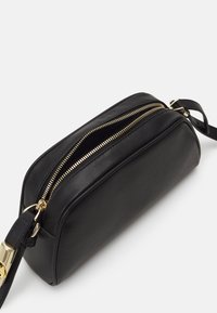 Geantă de umăr din piele naturală neagră, cu două fermoare superioare, accesorii de culoare aurie și o formă rectangulară elegantă. Textură netedă și curea robustă.