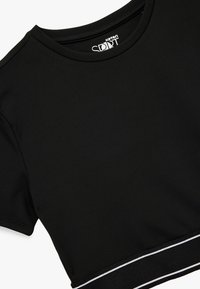 Mustapaitainen lyhythihainen crop top, joka on valmistettu joustavasta materiaalista. Paita sisältää pyöreän kaula-aukon ja erottuvan valkoisen raidoituksen vyötäröllä.