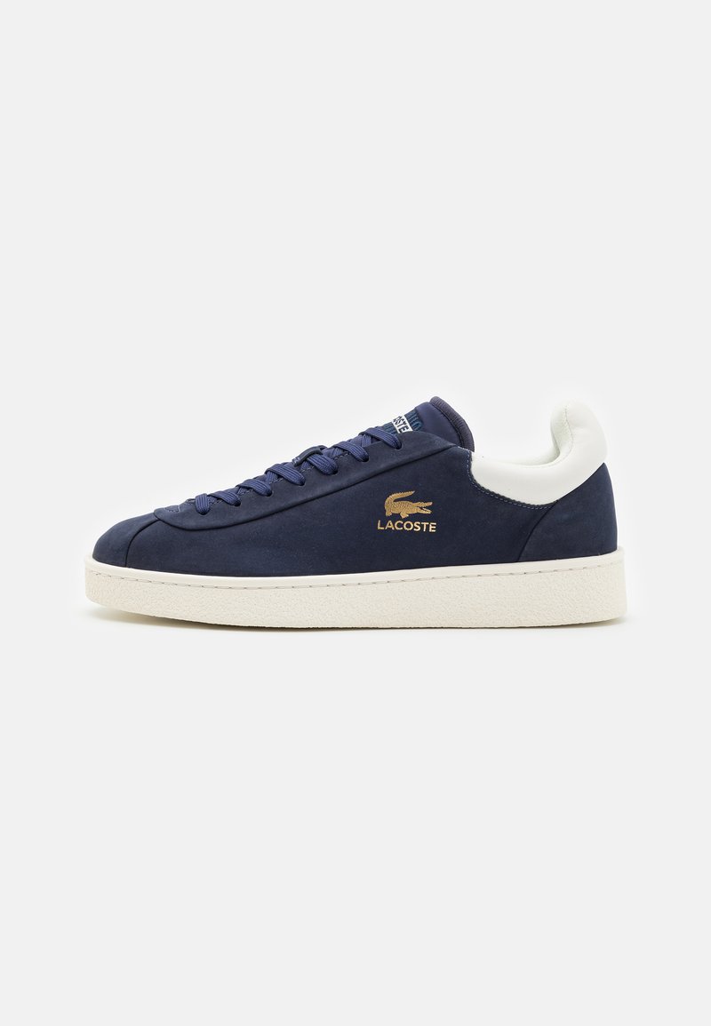 Adidas pantofii bleumarin cu superior din nubuc neted, detalii din piele albă și o talpă din cauciuc texturată bej, având un logo aurit.