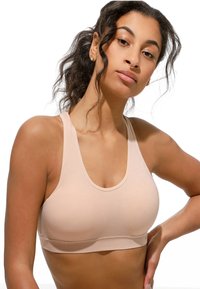 Sostenitore sportivo rosa chiaro realizzato in morbido tessuto elasticizzato, con scollatura a girocollo e spalline larghe. Design senza cuciture con hardware minimale.