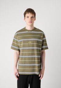 Maslinasto zeleni prugasti T-shirt s horizontalnim bijelim i crnim prugama; ima okrugli izrez i HUGO logo u zlatnoj boji na prsima.