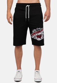 Zwarte katoenen shorts met een elastische tailleband, witte trekkoorden, zijzakken en een grote rood-witte graphic op de voorkant.