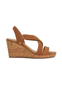Sandale compensée en daim beige avec des brides croisées et une semelle en liège. Comprend une semelle intérieure en cuir lisse et un subtil accent de logo sur le côté.