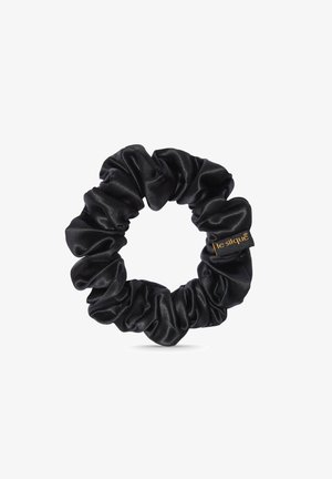 Chouchou en satin noir avec une texture lisse et un design froncé. Présente une petite étiquette logo dorée. Forme circulaire pour le coiffage des cheveux.