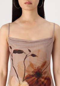 Robe sans manches en taupe clair, ornée de grandes imprimés floraux dans des nuances de beige et de brun. Texture lisse avec un design à encolure drapée.