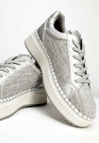 Sneaker grigie con tomaia in tessuto testurizzato, dettagli argentati e una suola spessa bianca con un bordo rialzato e cuciture in contrasto.