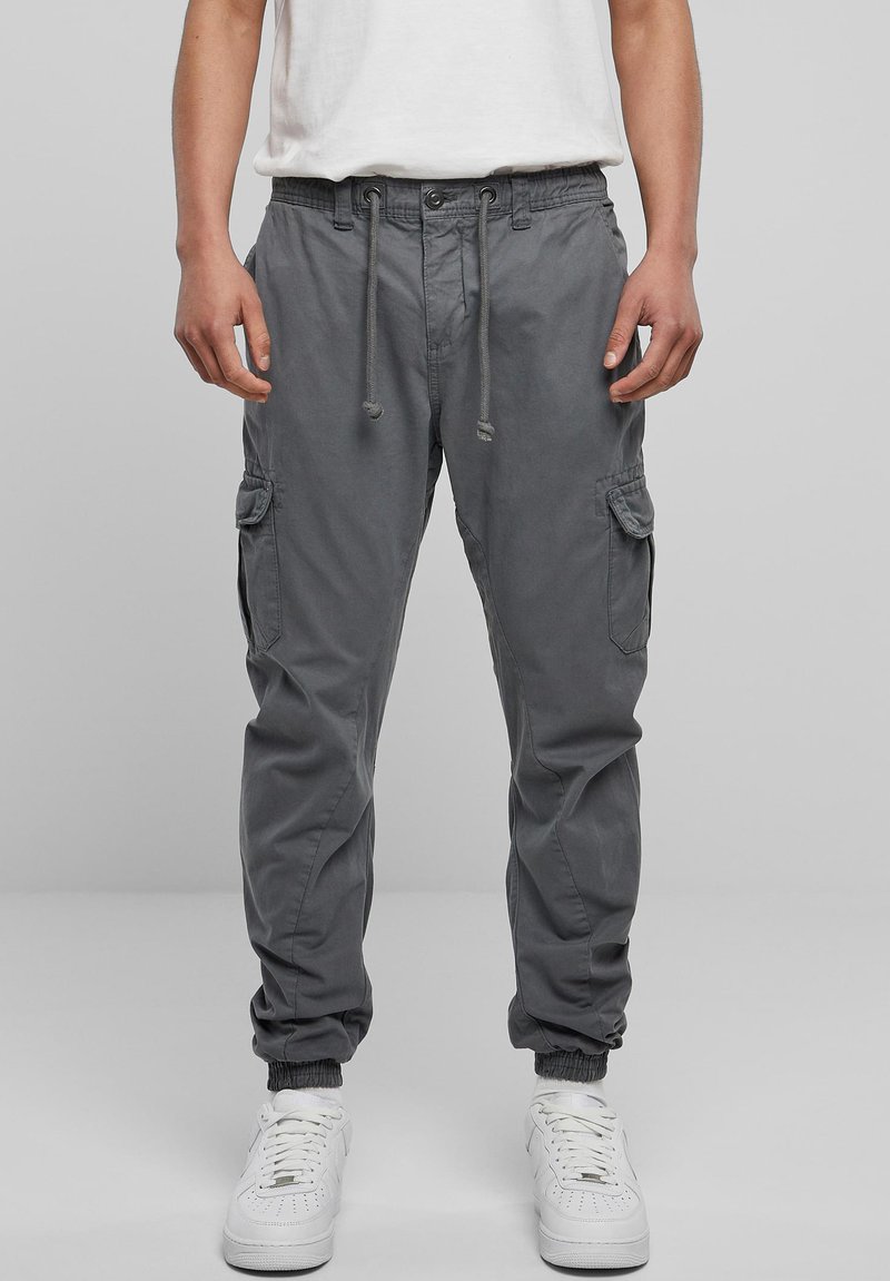 Grijze cargobroek met een elastische tailleband en trekkoord, voorzien van zijzakken en elastische boorden bij de enkels. Gekocht in combinatie met witte sneakers.